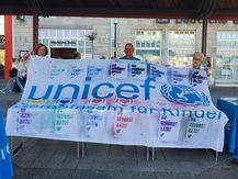 3 Menschen halten einen großen Banner von UNICEF hoch