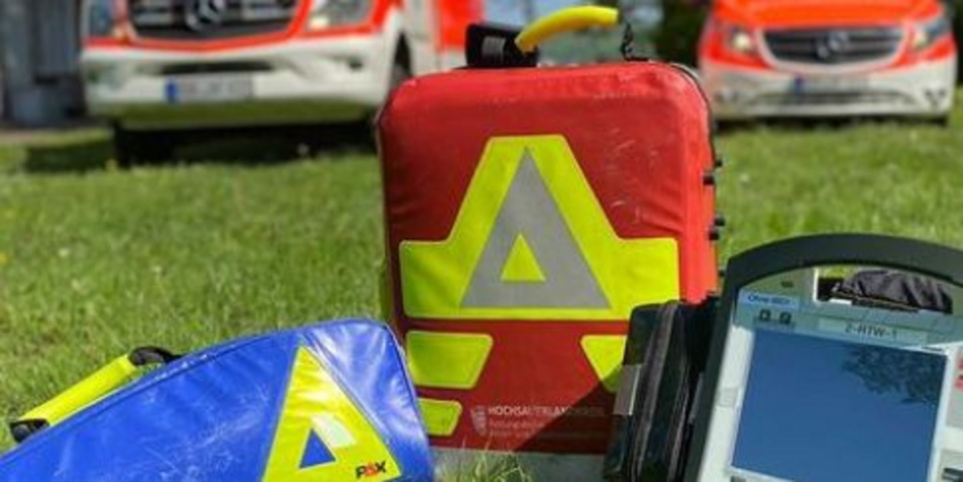 Ausrüstung des Rettungsdienst auf einer Wiese vor den Einsatzfahrzeugen